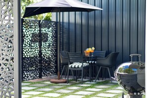 Eine Terrasse im Freien mit Grill, Stühlen und einem Tisch mit Obst.