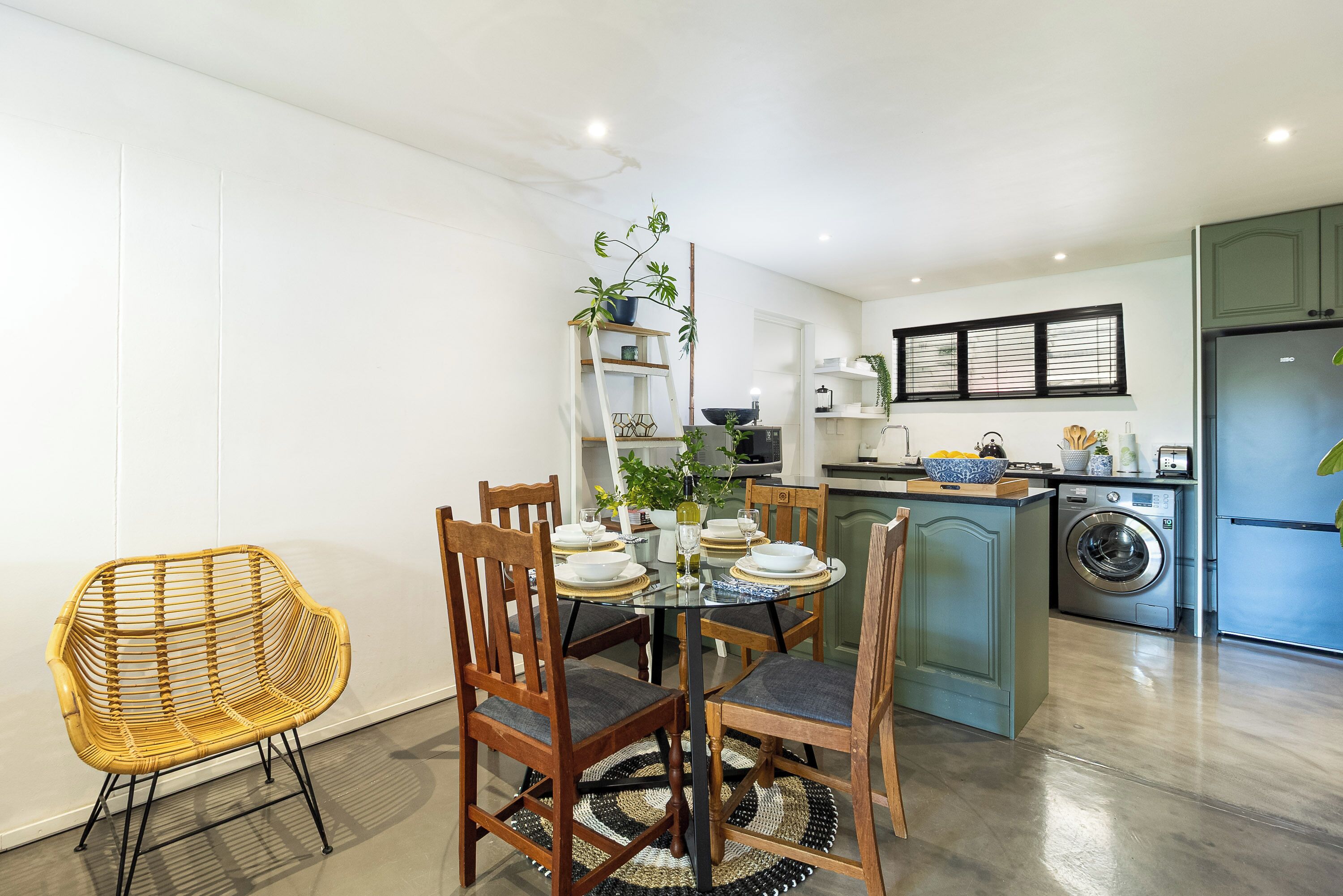 Een moderne keuken met een eethoek, waaronder een ronde tafel, stoelen en een wasmachine.