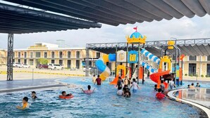 Un área de piscina con tobogán de agua y estructuras de juego.