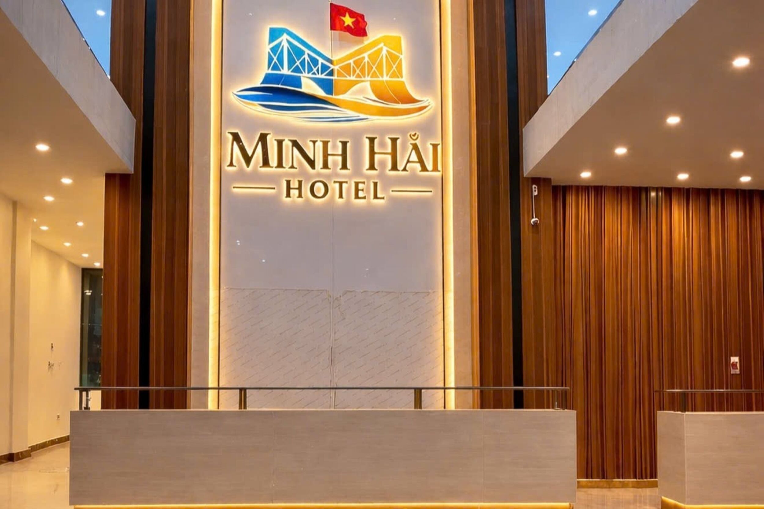 A hotel reception area with a prominent sign for Minh Hài Hotel, featuring a bridge and flag design.