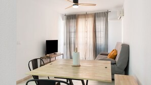 En moderne stue med spisebord, sofa, fjernsyn og loftventilator.