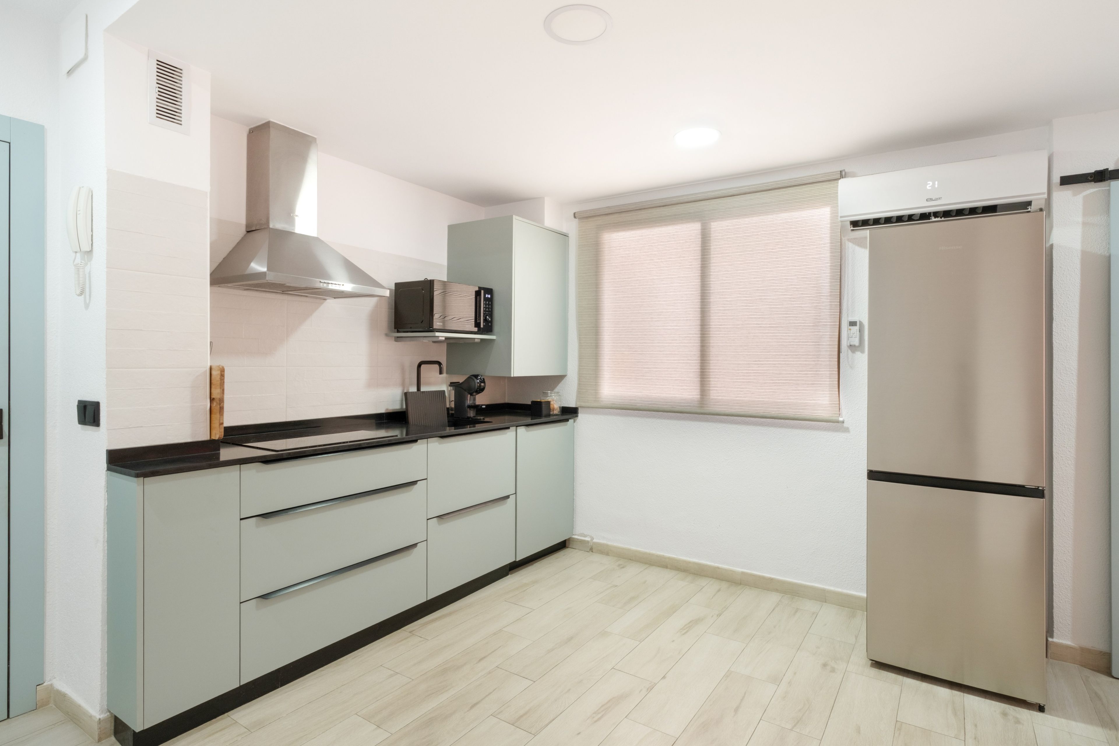 Una cocina moderna con microondas integrado, extractor de acero inoxidable y refrigerador de doble puerta.