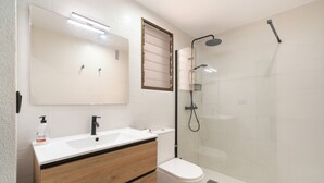 Et moderne badeværelse med et dobbelt vaskeskab, toilet og en bruseniche med glasvægge.