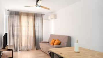 A living room with a sofa, a wooden table, a ceiling fan, and a TV.