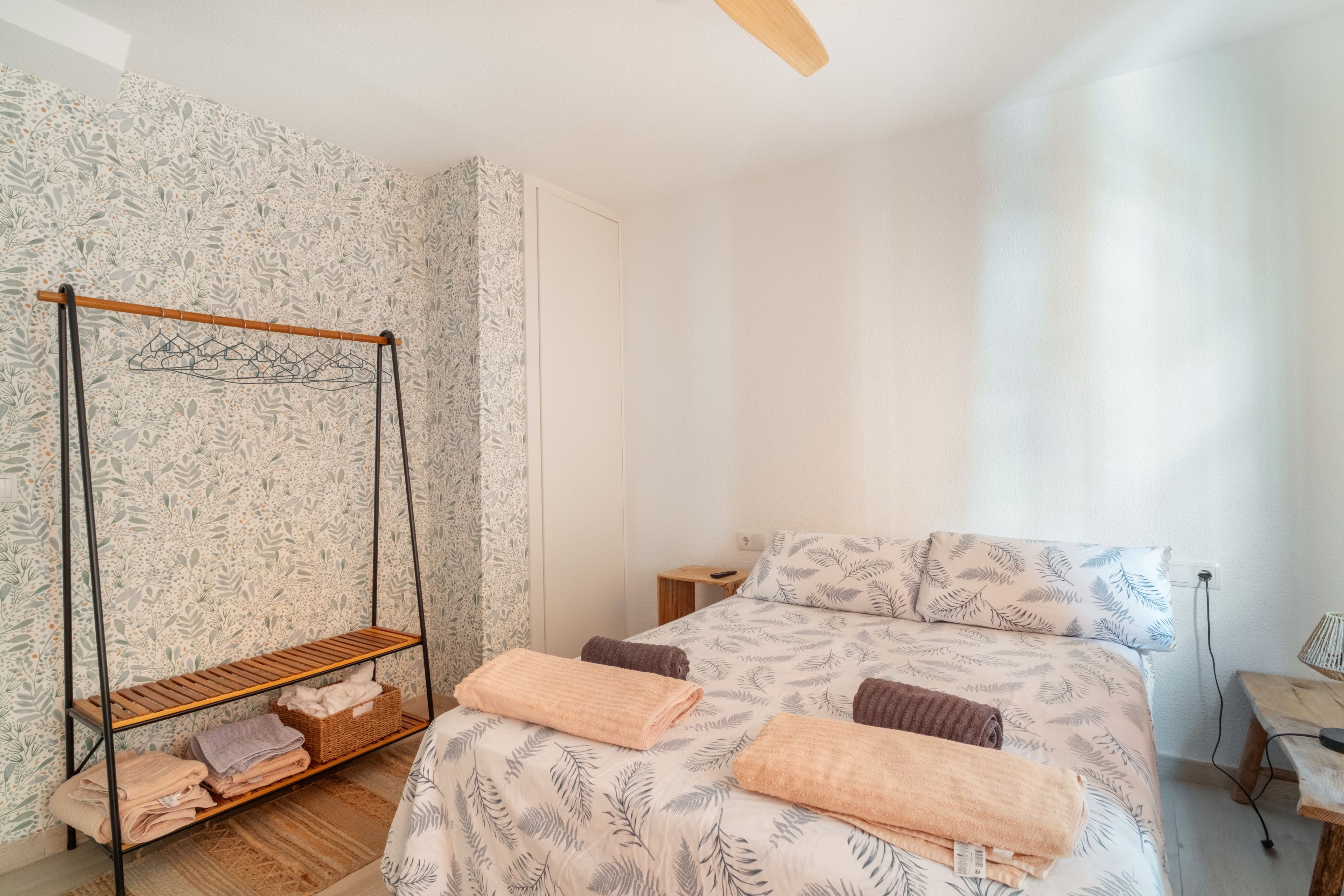 Une chambre à coucher avec un lit, un fauteuil suspendu, une petite table et une table de chevet.