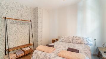 Une chambre à coucher avec un lit, un fauteuil suspendu, une petite table et une table de chevet.
