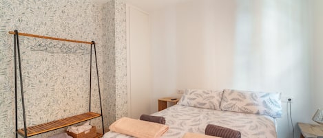 Une chambre à coucher avec un lit, un fauteuil suspendu, une petite table et une table de chevet.