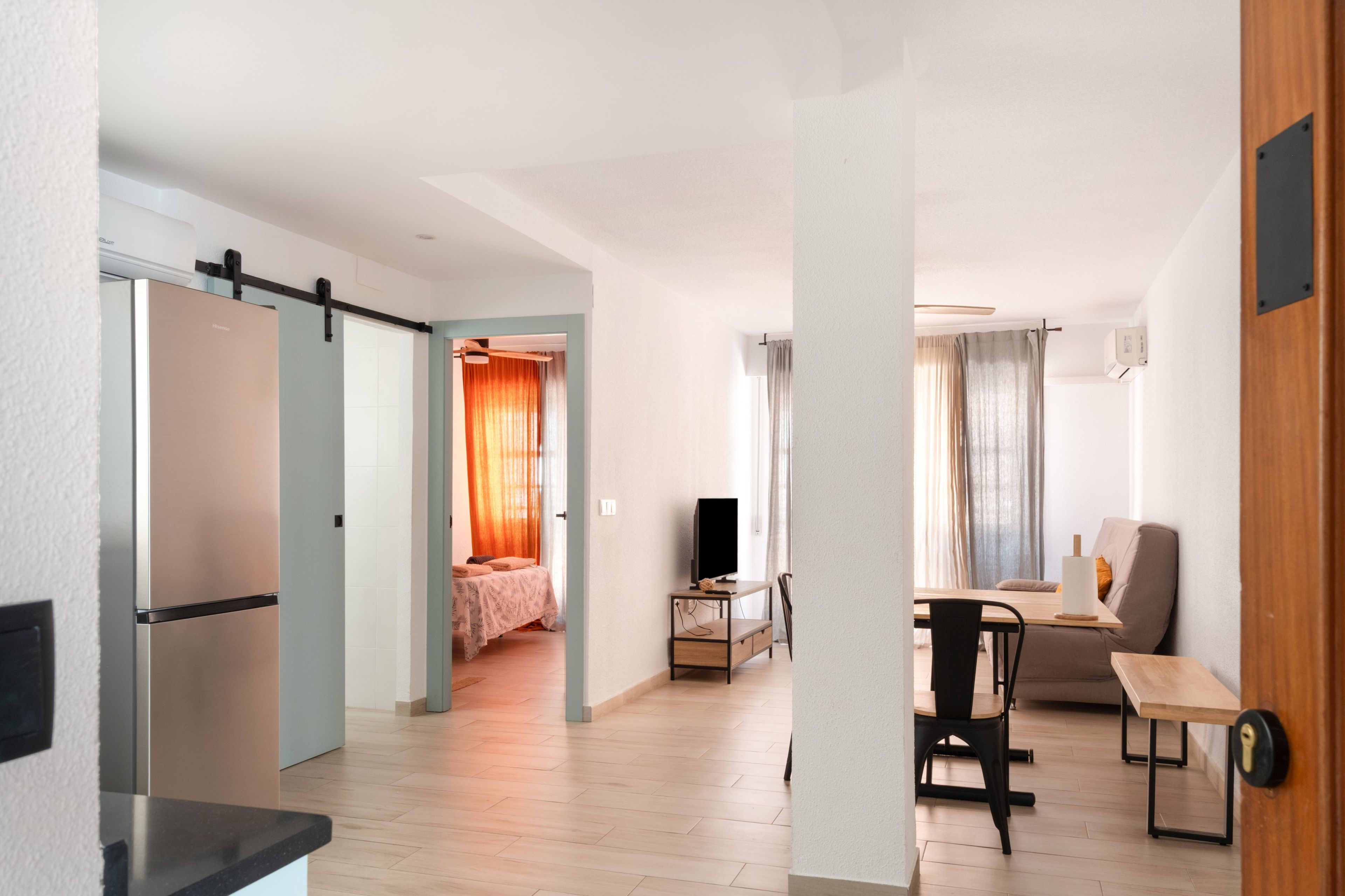 Un appartement moderne comprenant une cuisine, un coin repas et une chambre avec une grande fenêtre.