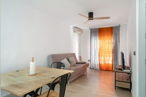En stue med sofa, spisebord, loftventilator og tv.