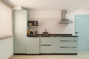 A modern kitchen with a built-in microwave, a stainless steel range hood, and a light blue door.