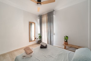 A modern bedroom with a bed, a bench, a potted plant, and a mirror.