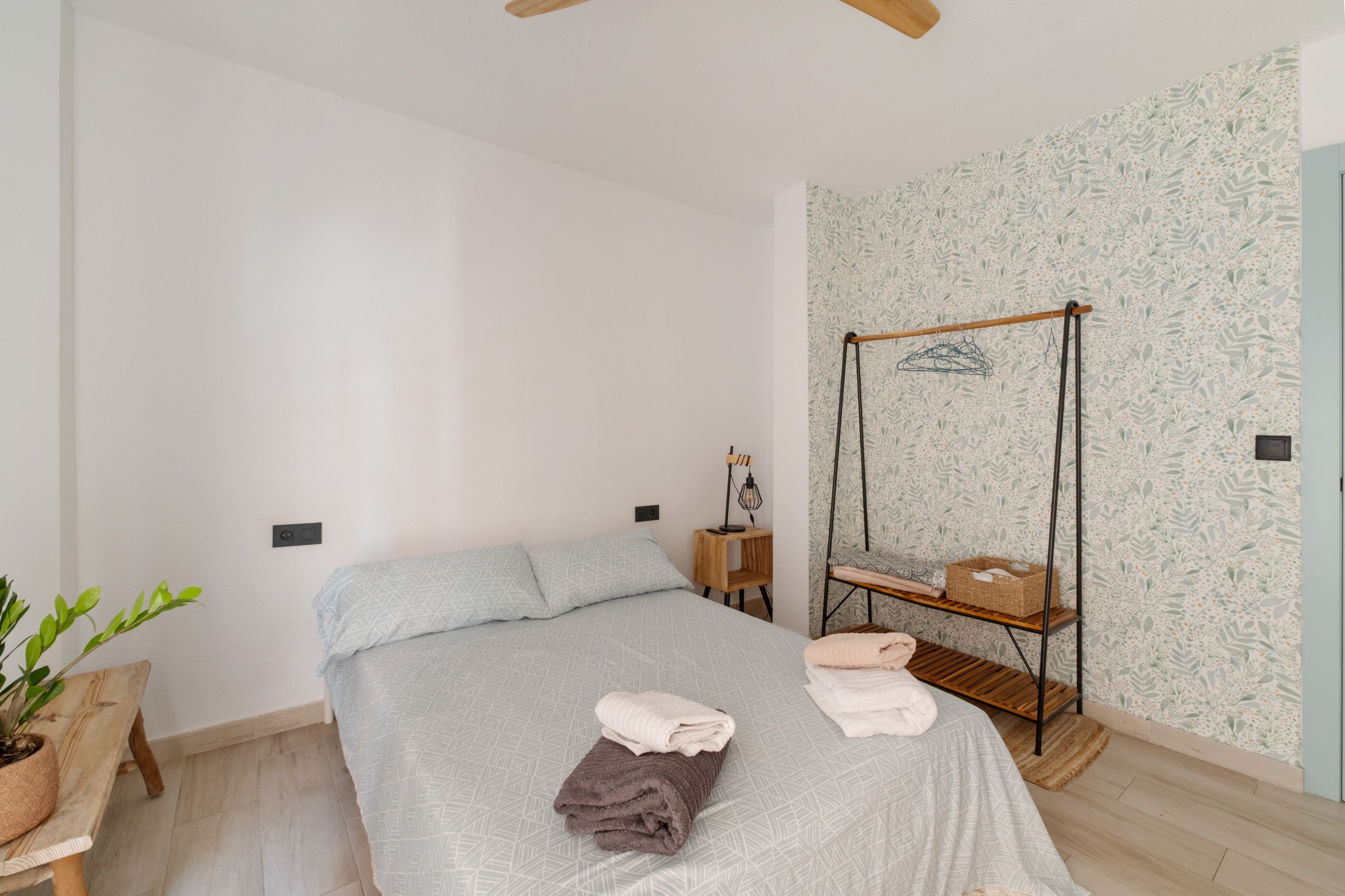 Ein Schlafzimmer mit einem Bett, einem Hängestuhl, einem kleinen Tisch und einer Topfpflanze.