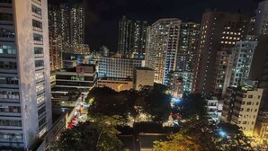Un paisaje urbano nocturno con rascacielos, una puerta tradicional y una calle bien iluminada.