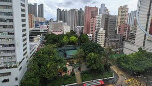 Zona urbana con edificios de gran altura, un parque verde y una carretera curva.