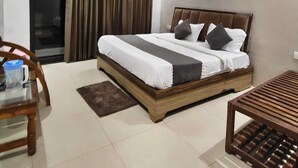Un dormitorio con cama, escritorio, silla, ventilador de techo y ventana con cortinas.