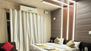 Un dormitorio moderno con cama, mesitas de noche, un sofá y cortinas.
