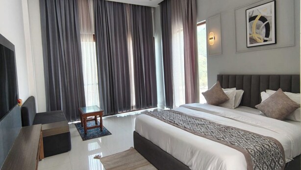 Un dormitorio moderno con una cama grande, un ventilador de techo, un televisor y una ventana con cortinas.