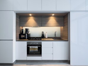 A modern kitchen with a built-in oven, a coffee maker, and a sink. - Modern Studio in Prime Location & JBR (Dubai Marina)