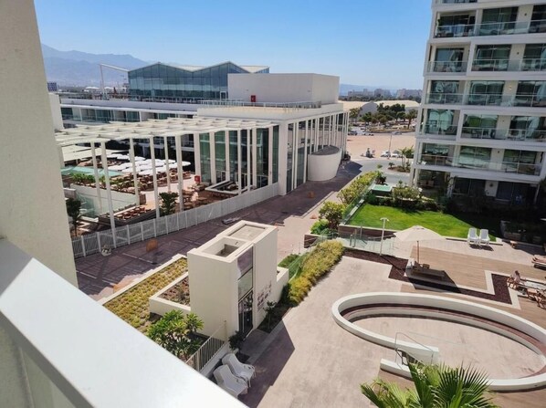 A modern building with a glass facade, outdoor seating area, and a landscaped courtyard. - Ocean's Edge Suite at 42 Eilat (Eilat)