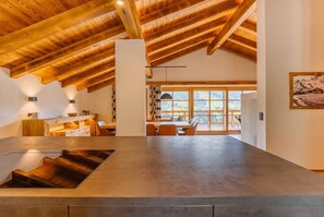 A modern interior with a high ceiling, a dining area with a view, and a staircase. - Premium Chalet Stella Maria (Mühlbach am Hochkönig)