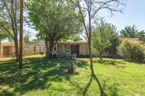 A stone building with a patio, surrounded by trees and grass.