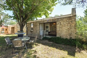 A stone building with a patio, outdoor seating, and a grill.