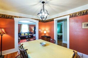 A dining area with a table, chairs, a bowl, a lamp, and a ceiling fan.