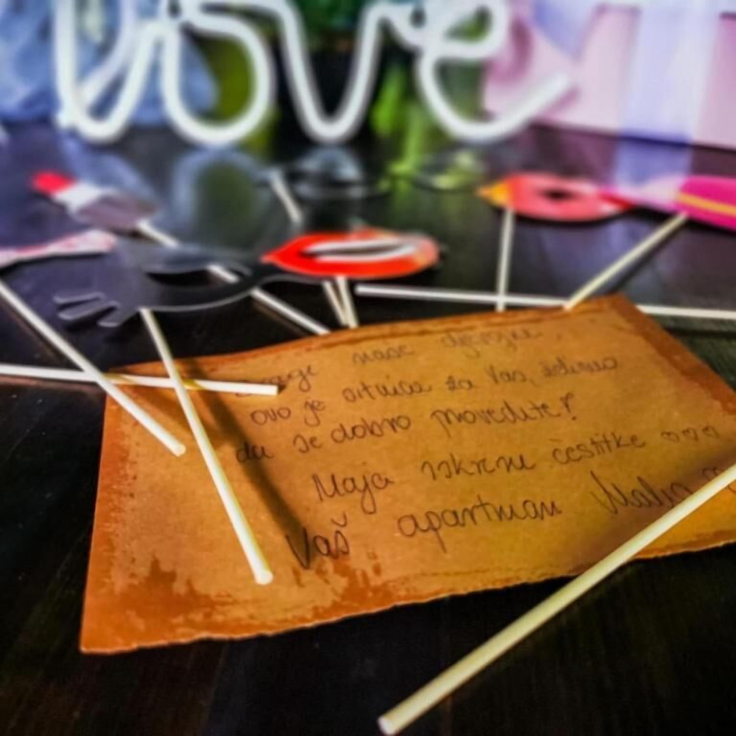 A handwritten note on a brown paper with a pen and a pair of scissors on a table.