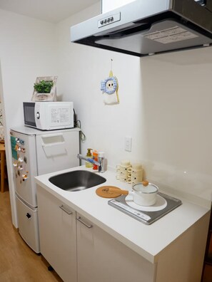 Eine Küche mit Mikrowelle, Herd, Spüle und einem kleinen dekorativen Gegenstand an der Wand.