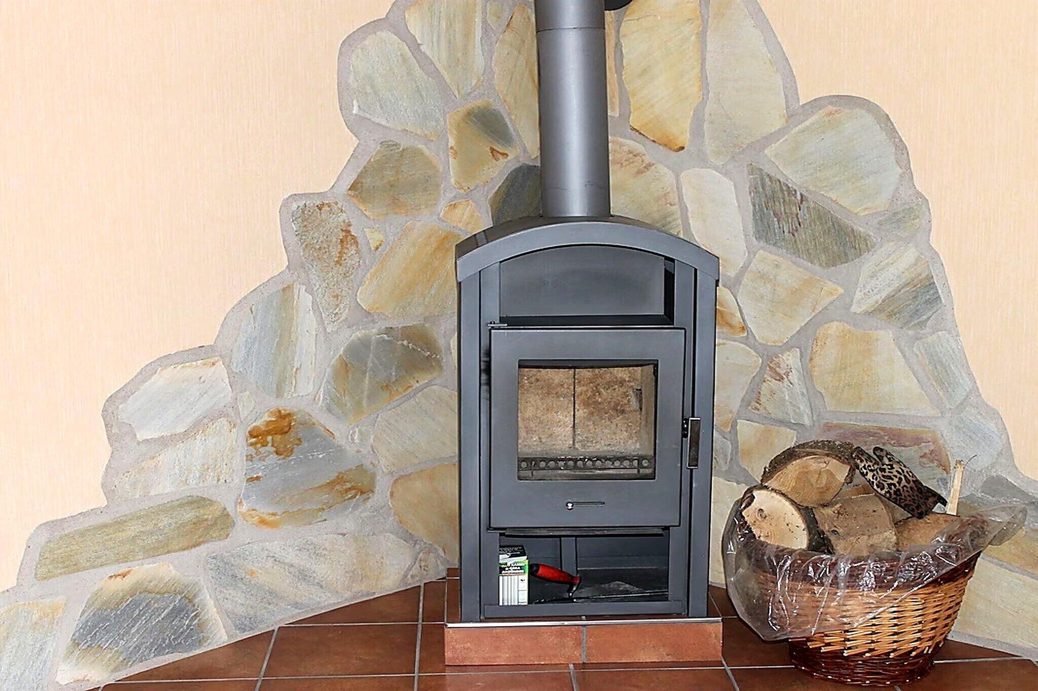 Eine Steinsäule mit Kamin, einem Holzkorb und einer Feuerzeugflasche.