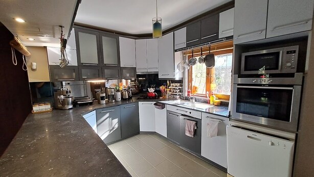 A modern kitchen with stainless steel appliances, a large island, and a window providing natural light.