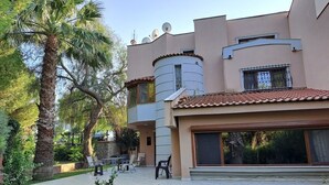 A modern building with a flat roof, large windows, and a patio area with outdoor furniture.
