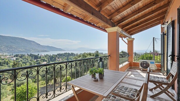 A balcony with a wooden pergola, a table with potted plants, a fan, and cushioned seating. - Apartment 'Villa Boho' with Sea View and Shared Garden (Kato Korakiana)