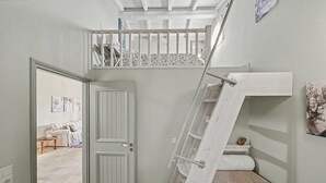 A room with a white door, a staircase, a bed, and a small table. - Apartment 'Villa Boho' with Sea View and Shared Garden (Kato Korakiana)