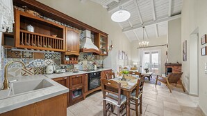 A kitchen with wooden cabinets, a large island, and a dining area with chairs. - Apartment 'Villa Boho' with Sea View and Shared Garden (Kato Korakiana)
