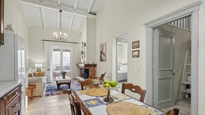 A dining area with a table set for four, a chandelier, and a fireplace in the background. - Apartment 'Villa Boho' with Sea View and Shared Garden (Kato Korakiana)