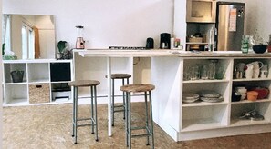 A kitchen with a bar area, stools, shelves with dishes, and a blender. - Townhouse in smiley-neighbourhood 2060 (Antwerpen)