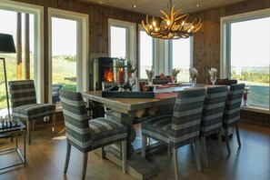 A dining area with a fireplace, plaid chairs, and a view of the outdoors. - Apartment on Golsfjellet with views of Jotunheimen (Gol)