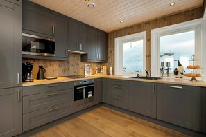 A modern kitchen with grey cabinets, a built-in oven, and a large window. - Apartment on Golsfjellet with views of Jotunheimen (Gol)
