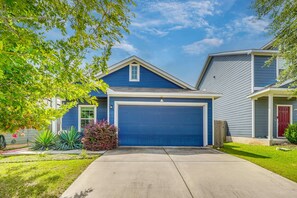 A residential house with a blue garage door, a front yard with landscaping, and a neighboring house. - South Austin Hub Near Airport & McKinney Falls! (Austin)