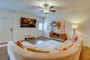 A living room with a ceiling fan, a television, a sofa, a side table, and a lamp. - South Austin Hub Near Airport & McKinney Falls! (Austin)