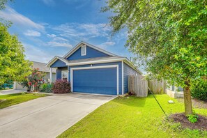 A residential house with a blue garage, a well-maintained lawn, and a tree in the front yard. - South Austin Hub Near Airport & McKinney Falls! (Austin)