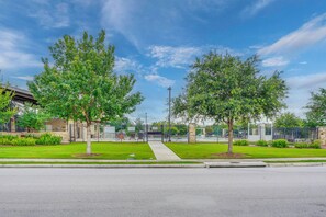 A street view with a sidewalk, trees, a fence, and a building in the background. - South Austin Hub Near Airport & McKinney Falls! (Austin)