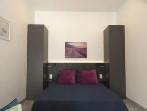 Un dormitorio moderno con una cama grande, dos mesitas de noche y un cuadro colgado en la pared.