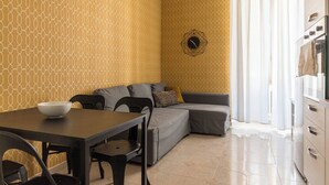 Un salon moderne avec une table à manger, un canapé et un mur orné d’un motif géométrique.