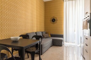 A modern living room with a dining table, sofa, and a geometric patterned wall. - Amazing Large Apartment in the Vatican Area (Roma)