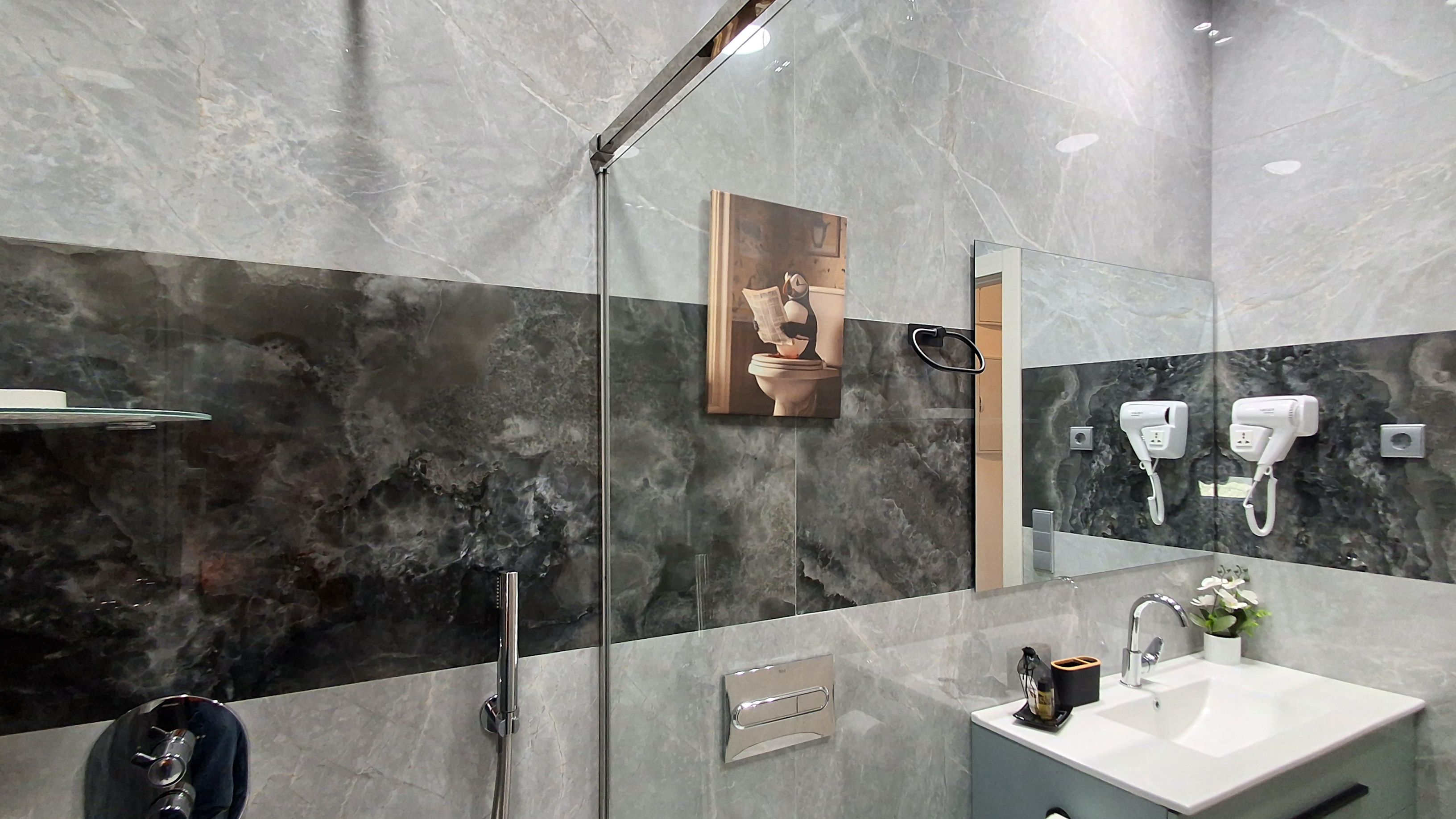 Ein modernes Badezimmer mit Glasdusche, Waschbecken mit Spiegel und Handtuchhalter.