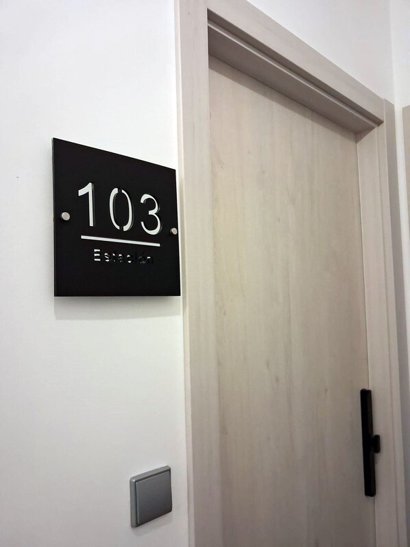 A black sign with the number 103 and the word 'Estacio' on a white wall. - Estación 103 1 bedroom, 1 bathroom apartment (Peñiscola)