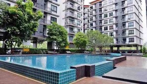 A residential building with a swimming pool, balconies, and greenery. - Living avenue condominuim (Saen Suk)