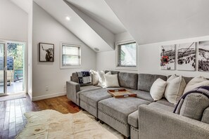 Ein modernes Wohnzimmer mit einem Ecksofa, einem großen Teppich und einer Wandgalerie zum Thema Skifahren.